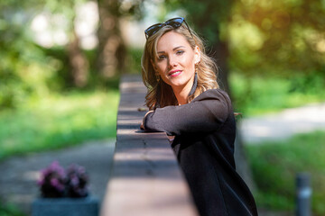 Wall Mural - fashion portrait of a stylish nice blonde female in sunglasses leaning on a railing of pedestrian bridge