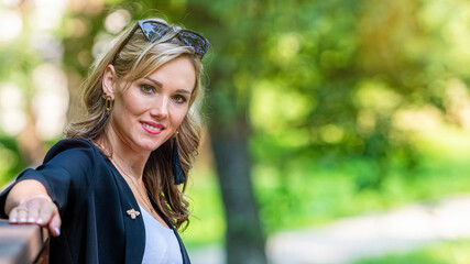 Wall Mural - fashion portrait of a stylish nice blonde female in sunglasses on a defocused park background