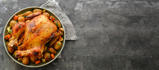 Whole baked chicken. Free space for text. Grey background. Chicken with potatoes, garlic and carrots. Top view