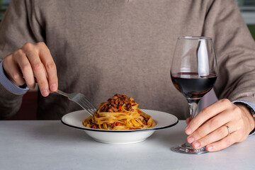 Poster - A man eating traditional italian pasta tagliatelle al ragù, also known as pasta bolognese. Red whine glass. Life style photo.