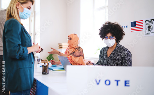 Fototapeta People with face masks voting in polling place, usa elections and coronavirus.
