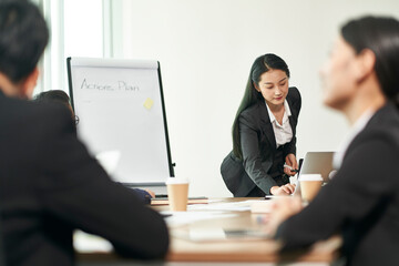 Wall Mural - young asian businesswoman presenting actions plans to team in office