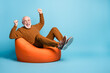 Portrait of his he nice attractive cheerful cheery glad excited lucky bearded grey-haired man sitting in bag chair rejoicing having fun isolated over blue pastel color background