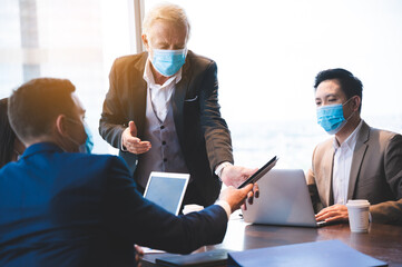 Wall Mural - A group of businessmen meeting a work plan in modern office By wearing a surgical mask to prevent the spread of the virus, new normal lifestyle for business work