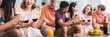 © LIGHTFIELD STUDIOS - collage of joyful multicultural friends talking while holding glasses of red wine in kitchen, panoramic concept