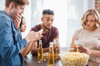 © LIGHTFIELD STUDIOS - selective focus of multiethnic friends chatting on mobile phones near beer and popcorn during party
