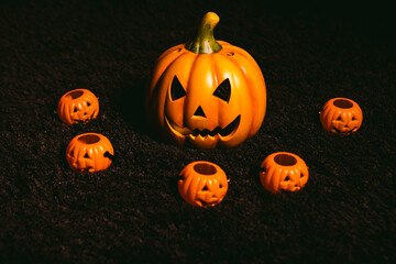 Jack-o-lantern pumpkin on a rug surrounded by other small pumpkins. Halloween concept