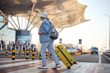 Wall Mural - Senior female tourist walking across the crosswalk