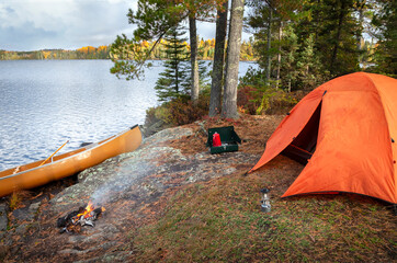 campsite with orange tent on northern minnesota lake during an autumn morning