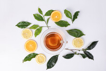 Different Types Of Fresh Raw Green Tea Leaf Flower Bud Lemon Orange Slice Transparent Glass Teacup Saucer Liquid Tea On White Background Top View