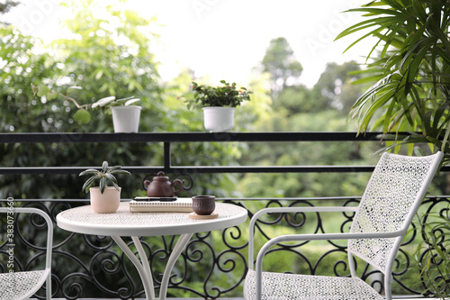 cup with plants in pots with notebook on white metal table at balcony outdoor