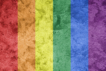 Rainbow LGBTQ or gay pride flag on decorative plaster or concrete texture. Abstract background.