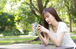 © NONTANUN - Asian women are using smartphones happily in the park. Concept of happy life of the new generation