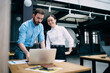 © BullRun - Amused young business partners typing on laptop at office