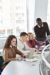 Wall Mural - Vertical side view portrait of multi-ethnic group of students using laptops while studying in college