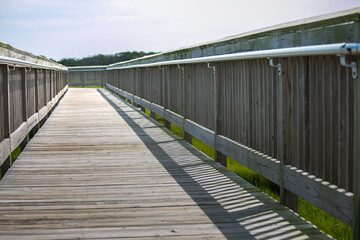  Wooden boardwalk with metal railings over coastal marsh