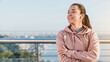 © InsideCreativeHouse - Happy lady jogger is resting after workout standing on the bridge against city landscape