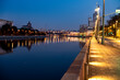 river embankment of a large metropolis at dawn with glowing lanterns reflections in the river