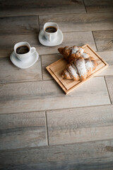 Fresh pastries croissants with chocolate on a wooden board and two cups of black coffee. Romantic breakfast