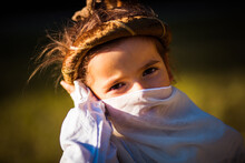 Little Girl With A Scarf Over Her Mouth Posing In Nature.
