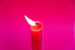 One burning red candle on a red background - Advent, birthday or christmas scene
