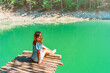 © KseniaJoyg - Beautiful girl with long hair in a dress on a bridge above a mountain lake with clear water and a view of a green forest. Copy space