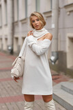 Fototapeta Konie - Elegant young female model with makeup and hairstyle standing and posing at city street. Autumn fashion