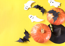 Halloween Composition Of Pumpkins, White Ghost, Bats, Witch Hat On Yellow Background. Home Handmade Decor Halloween