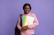 © Prostock-studio - Smiling black female student with workbooks and backpack posing on purple background
