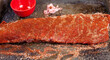 Baby back ribs prepared with a spice rub all over it, membrane removed, on a metal sheet pan with an empty bowl of spices