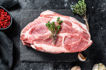 Raw pork neck chop meat with herb leaves and spices. Black background. Top view