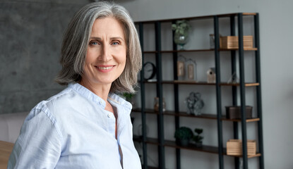 Wall Mural - smiling confident stylish mature middle aged woman standing at home office. old senior businesswoman