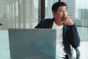 Wall Mural - Serious asian business man working on laptop in meeting room.