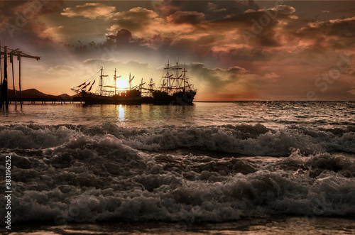 group of pirate sailing ships at sunrise