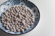 Raw tapioca bubble pearl for making boba milk tea on a plate with blue pattern.
