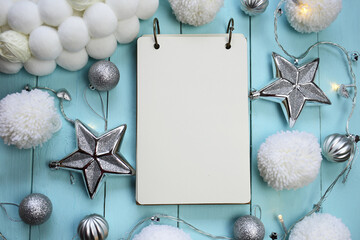 Sticker - Christmas and New Year Mockup.Winter to-do list.empty notebook, silver decorative ornaments and white pompons on a blue wooden background.Winter festive cozy flat lay.Winter holiday list