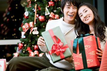 young man and woman with the Christmas tree and gift boxes