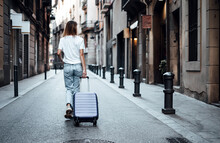 Young Traveling Woman With Suitcase On A Sunny City Street. Traveler On Vacation.