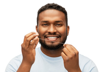 health care, hygiene and people concept - smiling african american young man with dental floss cleaning teeth over white background