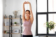 © Syda Productions - sport, fitness and healthy lifestyle concept - smiling young woman stretching arms at home