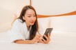 © siraphol - Portrait beautiful young asian woman use smart mobile phone on bed