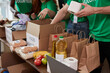 group of diverse people sort through donated food items while volunteering in community, they use cardboard boxes for collecting donation