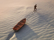 A Man Drags A Boat Through The Desert
