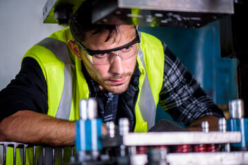 Caucasian engineer mechanic man checking for maintenance pressing metal machine by laptop at factory, worker at industrial concept