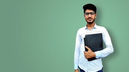 Young male college student smiling with holding laptop and documents in hands