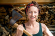 © Kirill Gorlov - Young adult beautiful happy attractive caucasian brunette woman portrait have fun enjoy holding old rusty axe chopping firewood at wood store on backyard. Feminine women equality empowerment concept