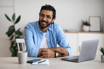 Wall Mural - Freelance Career. Handsome Indian Guy Sitting At Laptop In Home Office