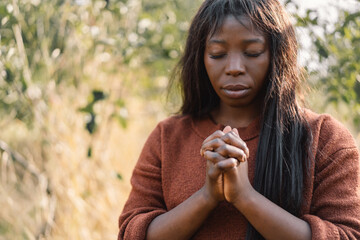 Wall Mural - Afro Girl closed her eyes, praying. Hands folded in prayer concept for faith, spirituality and religion