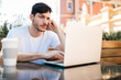 © Mego-studio - Young man using his laptop in a coffee shop.