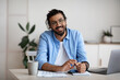© Prostock-studio - Happy Indian Guy Sitting At Desk In Home Office, Smiling At Camera